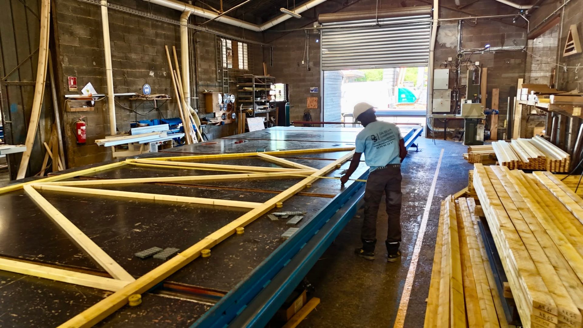 Charpentier Da Silva assemblant une charpente dans l'atelier de Lons